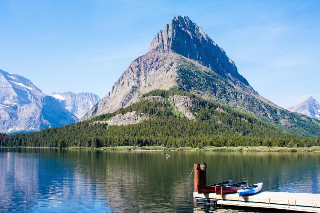 Rugged peak rising above a calm lake with kayaks at a wooden dock