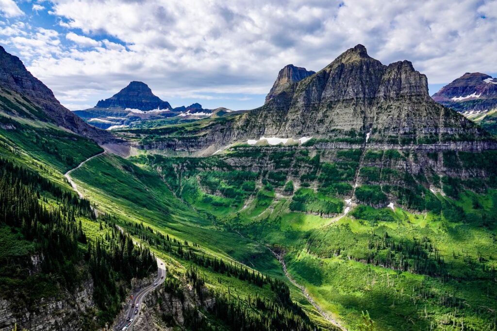 Mountain road winding along a green valley below jagged peaks